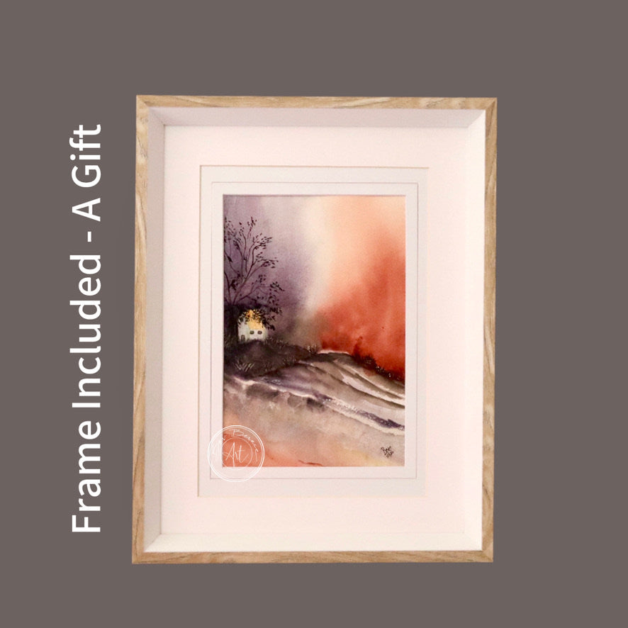 Watercolour painting of a small white house nestled into a hillside with a dramatic sunset sky in warm hues of orange and purple, framed in a light wood frame with a white mat.