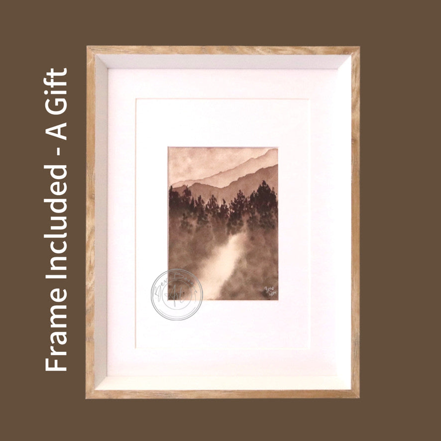 Monochromatic watercolour painting of a misty mountain landscape with silhouetted trees in the foreground, framed in a light wood frame with a white mat.