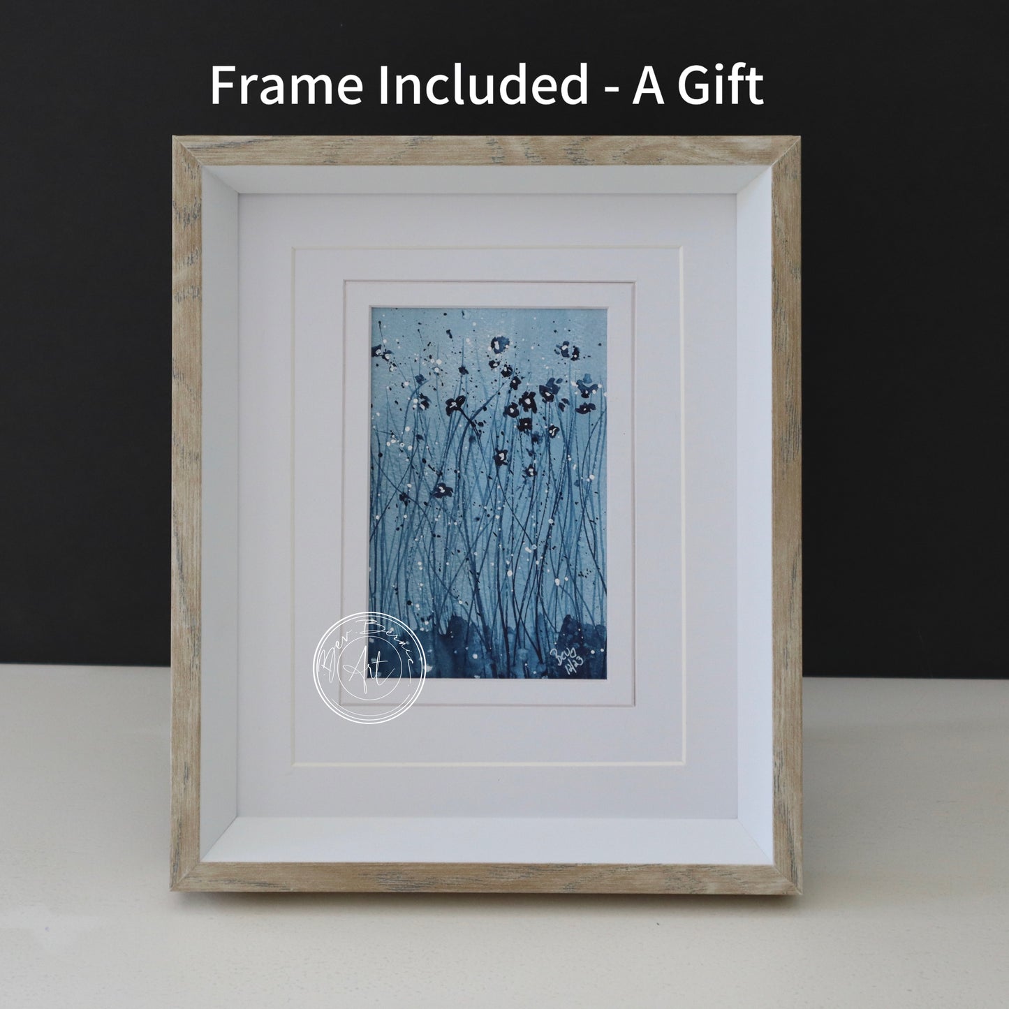 Abstract watercolour painting of dark blue flowers on thin stems with white specks against a textured, off-white background, framed in a light wood frame with a white mat.