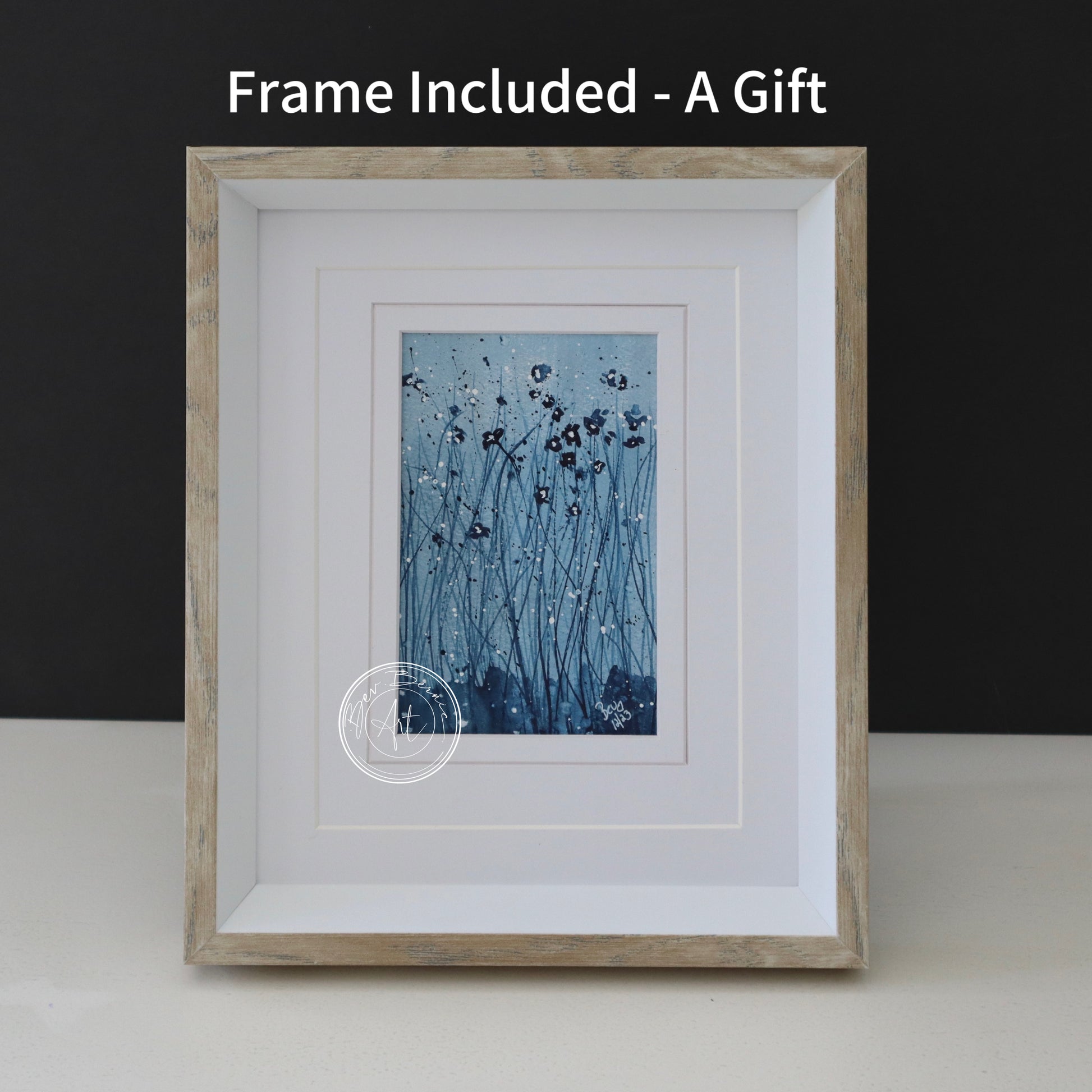 Abstract watercolour painting of dark blue flowers on thin stems with white specks against a textured, off-white background, framed in a light wood frame with a white mat.