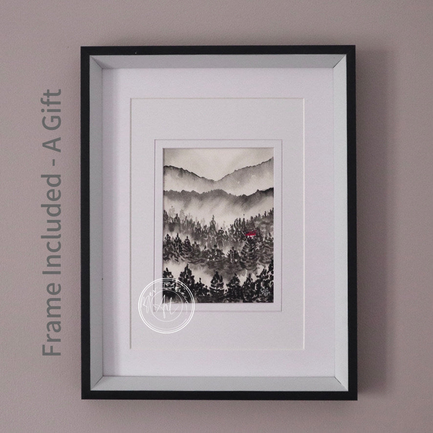 Monochromatic watercolour painting of a misty mountain landscape with a dense forest in the foreground, featuring a single red house roof, framed in a black frame with a white mat.