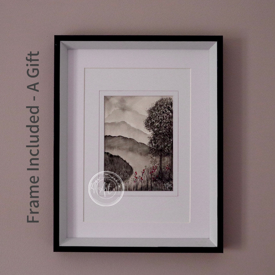 Monochromatic watercolour painting of a misty mountain landscape with a prominent tree on the right and a few small red flowers in the foreground, framed in a black frame with a white mat.