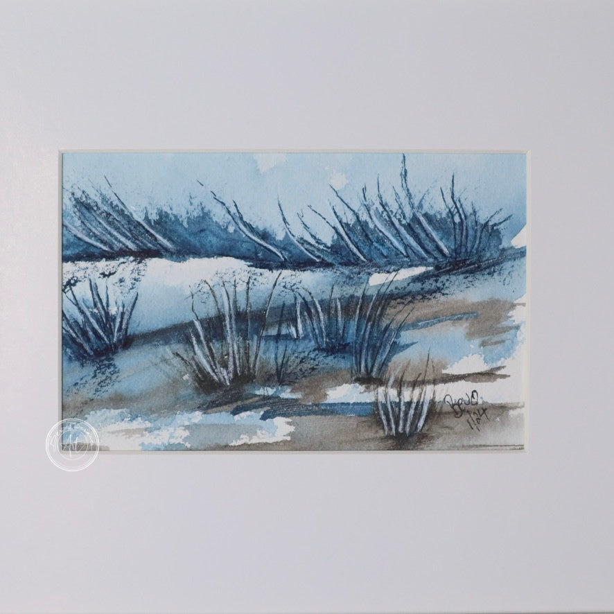 Three small square watercolor paintings in a row, depicting a minimalist winter landscape with blue, gray, and brown tones. The paintings are framed in a light wood frame with a wide white mat. Each painting shows a different aspect of the landscape, including water, reeds, and distant trees.