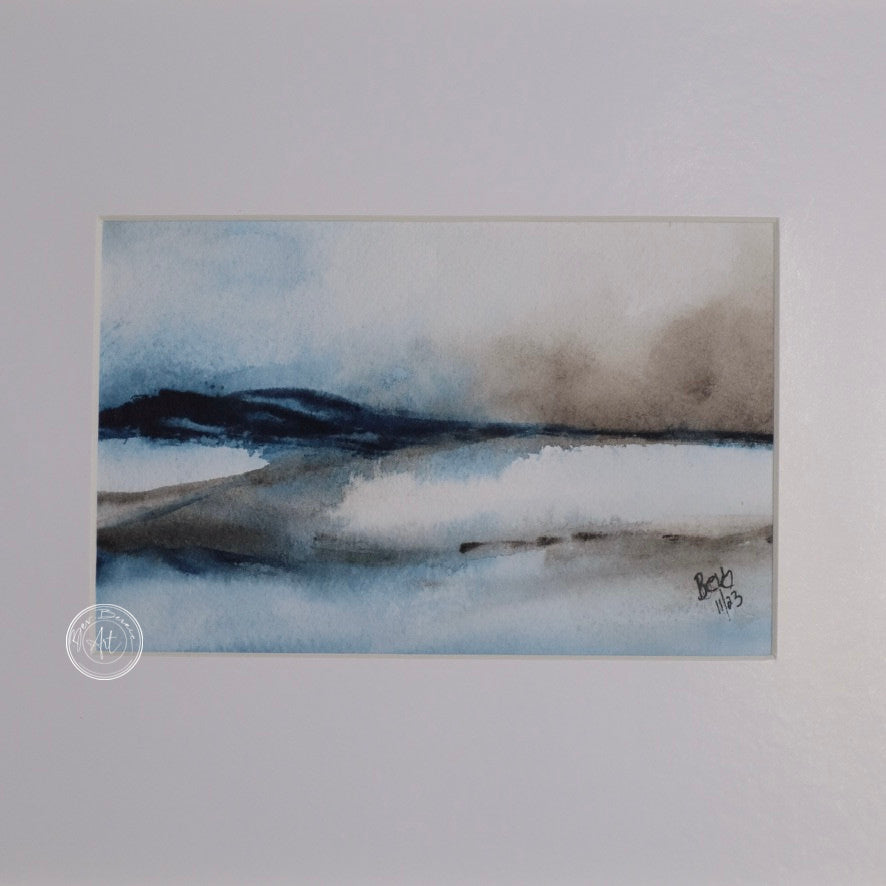 Three small square watercolor paintings in a row, depicting a minimalist winter landscape with blue, gray, and brown tones. The paintings are framed in a light wood frame with a wide white mat. Each painting shows a different aspect of the landscape, including water, reeds, and distant trees.