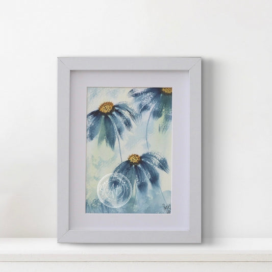 Framed artwork of blue flowers with gold centers on a white wall.