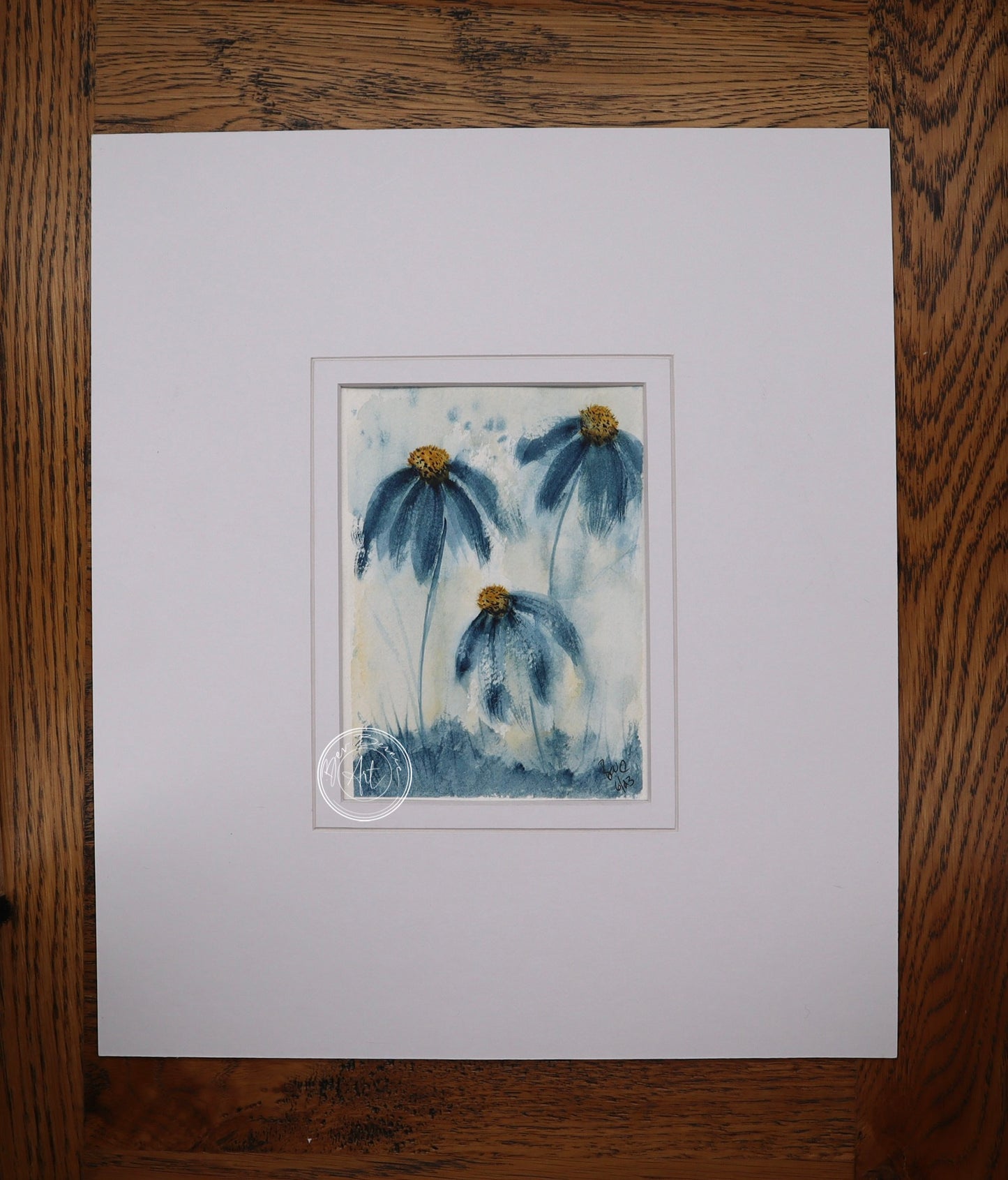 Painting of three blue daisy-like flowers with yellow centres and long stems, rising from a patch of blue-green grass against a light blue and white background.