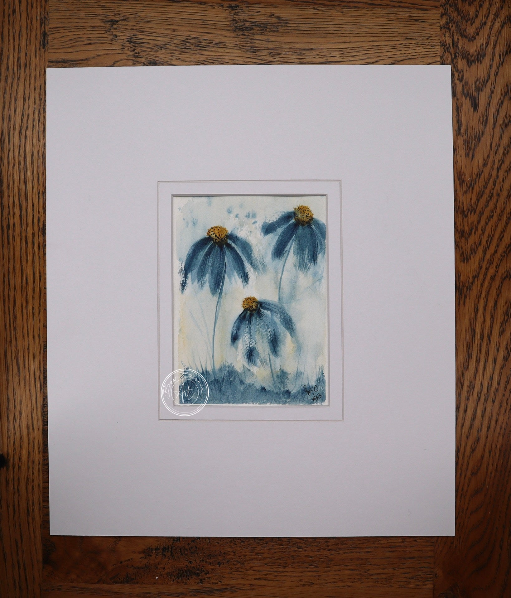 Painting of three blue daisy-like flowers with yellow centres and long stems, rising from a patch of blue-green grass against a light blue and white background.