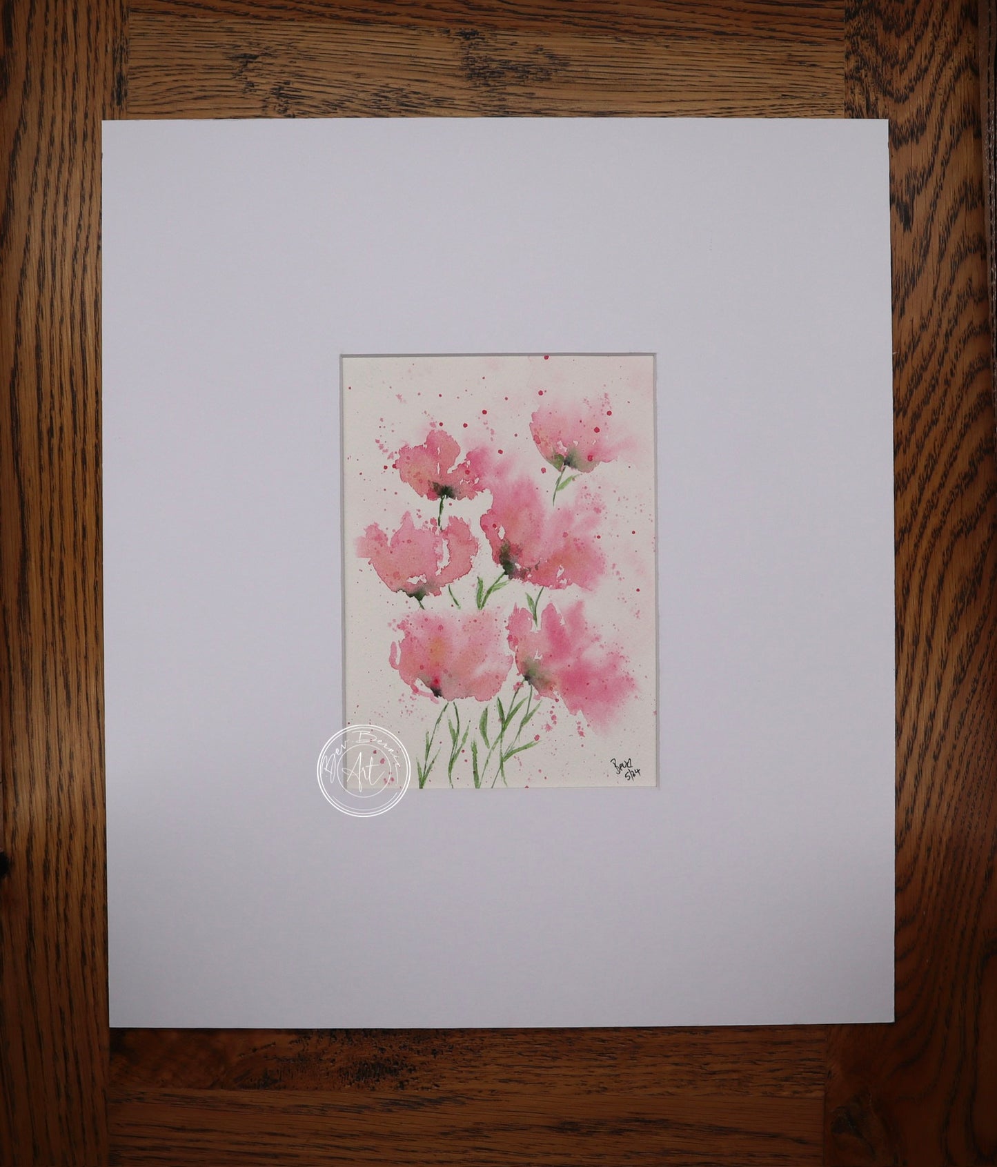 Watercolour painting of five pink poppies with delicate green stems, splattered with pink paint on a white background.