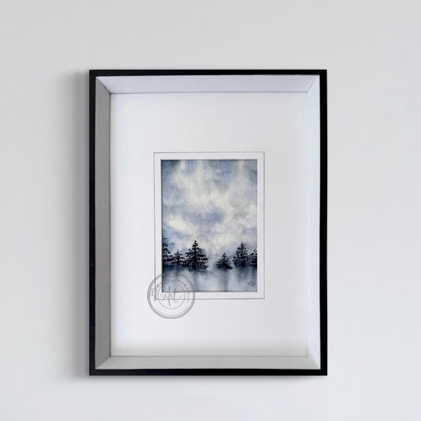 Framed artwork of trees in a misty landscape on a white wall