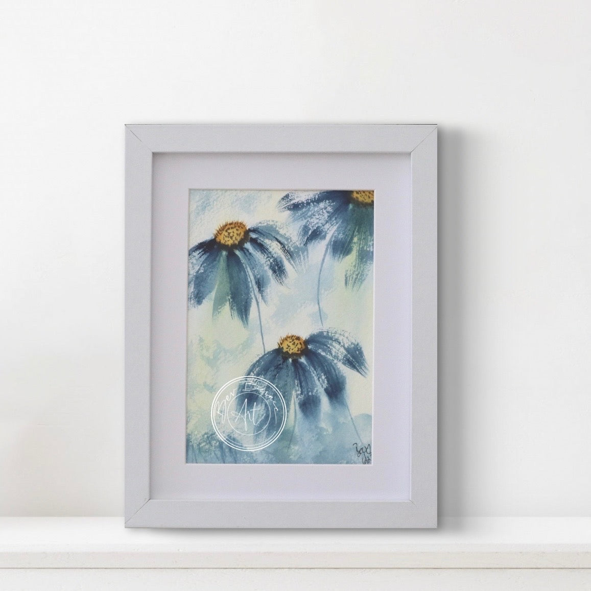 Framed artwork of blue flowers with gold centers on a white wall.