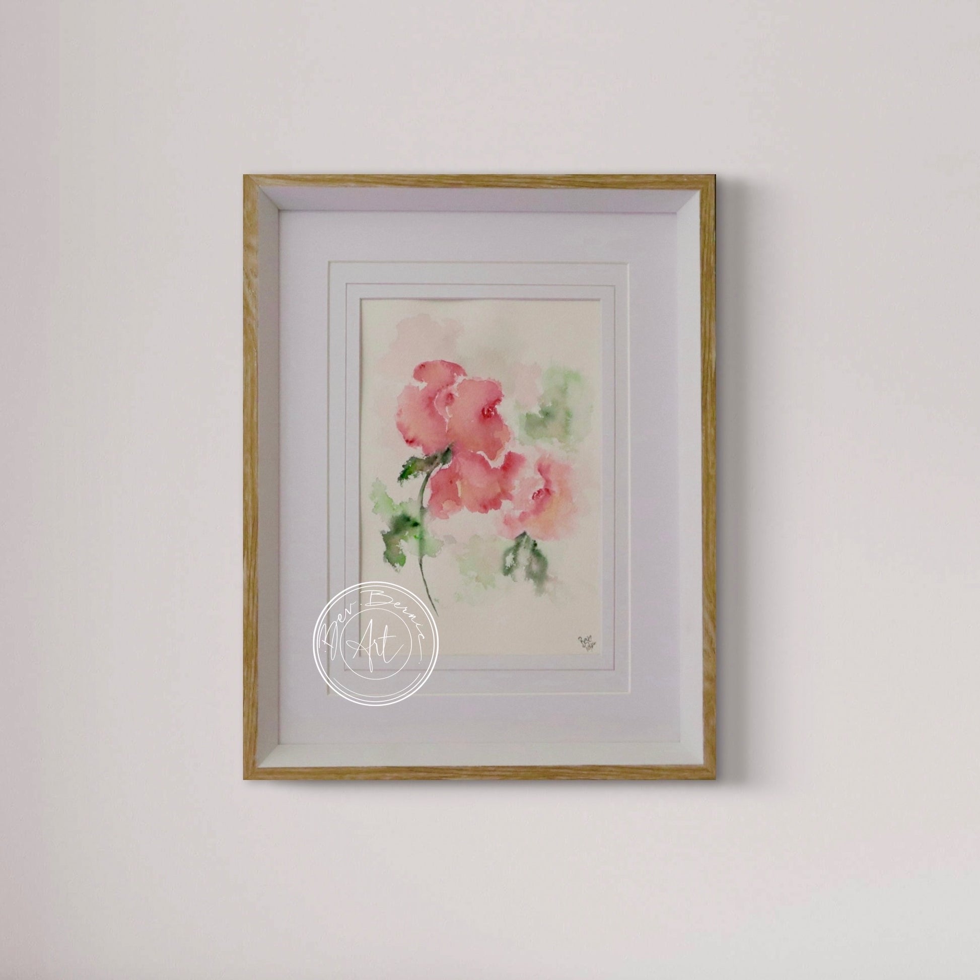 Framed watercolor painting of pink flowers on a white wall