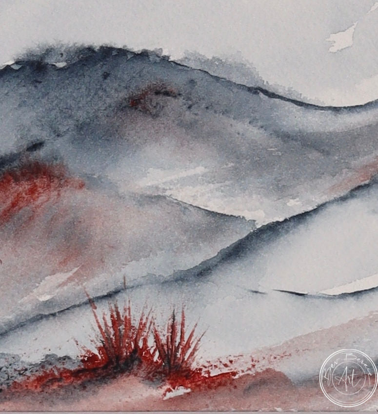Watercolour painting of a rolling landscape with blue-grey hills and splashes of red, possibly representing desert shrubs, in the foreground.